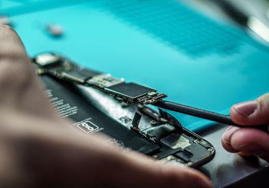 Certified technician repairing a laptop and smartphone at Al Barsha Electronics repair shop in Al Barsha, Dubai